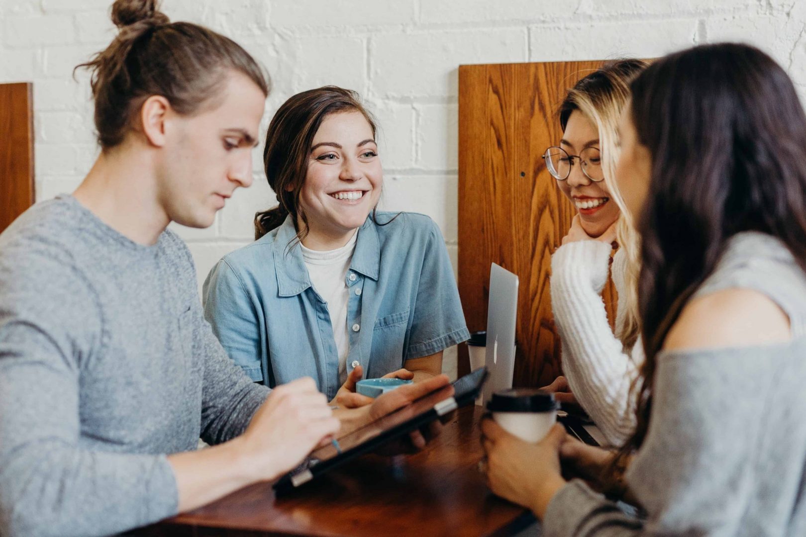 como engajar novos funcionários - colegas sorridentes de trabalho sentados em conjunto ao redor de uma mesa