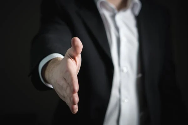 imagem de homem com terno esticando a mão como forma de "fechar contrato" para ilustrar blogpost sobre como aumentar vendas de uma empresa