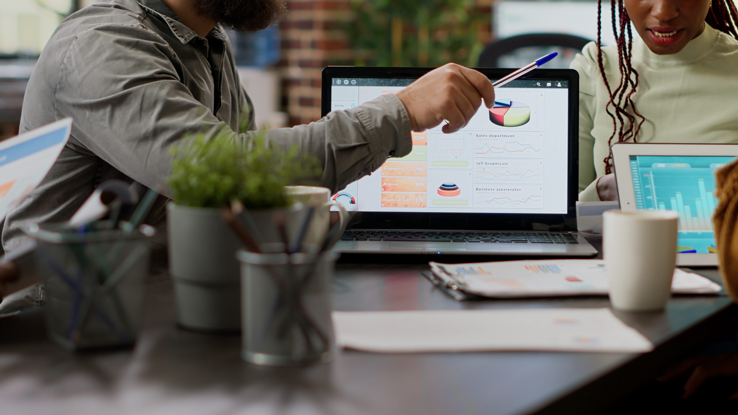 homem com caneta apontada para cima em frente a computador para ilustrar blogpost sobre análise de marketing